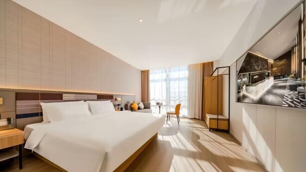 Une chambre d’hôtel moderne dotée d’un grand lit, d’un bureau et d’un coin salon.