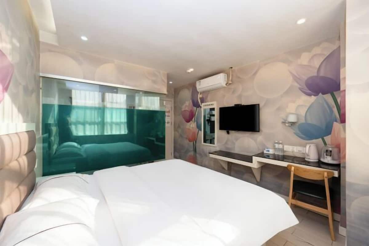 Ein modernes Hotelzimmer mit einem großen Bett, einem Schreibtisch mit Stuhl, einem Flachbildfernseher und einem Fenster mit Stadtblick.