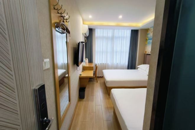 A hotel room with two beds, a desk, a chair, a television, and a mirror.