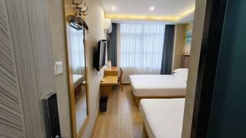 A hotel room with two beds, a desk, a chair, a television, and a mirror.