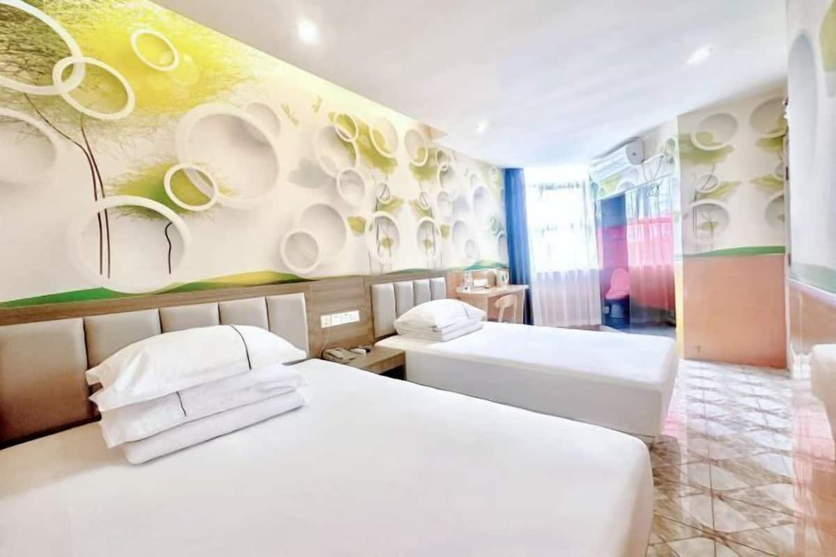 Ein Hotelzimmer mit zwei Betten, einer Wand mit kreisförmigen Mustern, einem kleinen Tisch und einem Stuhl.
