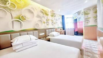 A hotel room with two beds, a wall with circular patterns, a small table, and a chair.