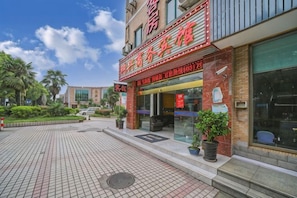 A hotel with a red sign, a tiled entrance, and potted plants. - Hongxing Business Hotel (Shanghai)
