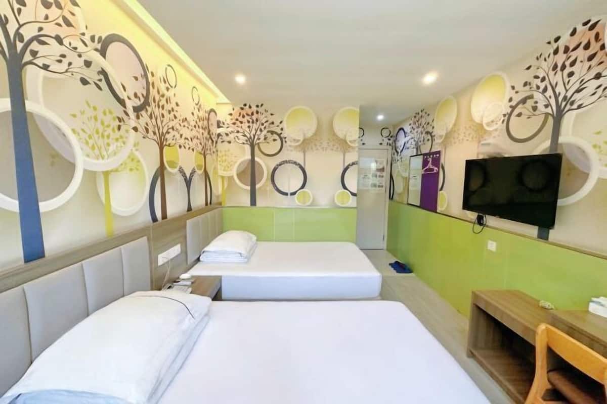 Ein Hotelzimmer mit zwei Betten, einem Fernseher und einer Wand mit kreisförmigen Mustern und Bäumen.