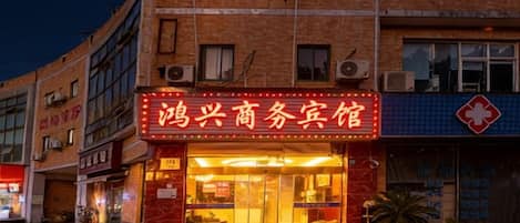 A building with a prominent red sign, multiple windows, and air conditioning units.