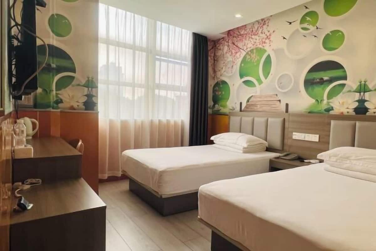 Ein Hotelzimmer mit zwei Betten, einem Schreibtisch und einem großen Fenster.