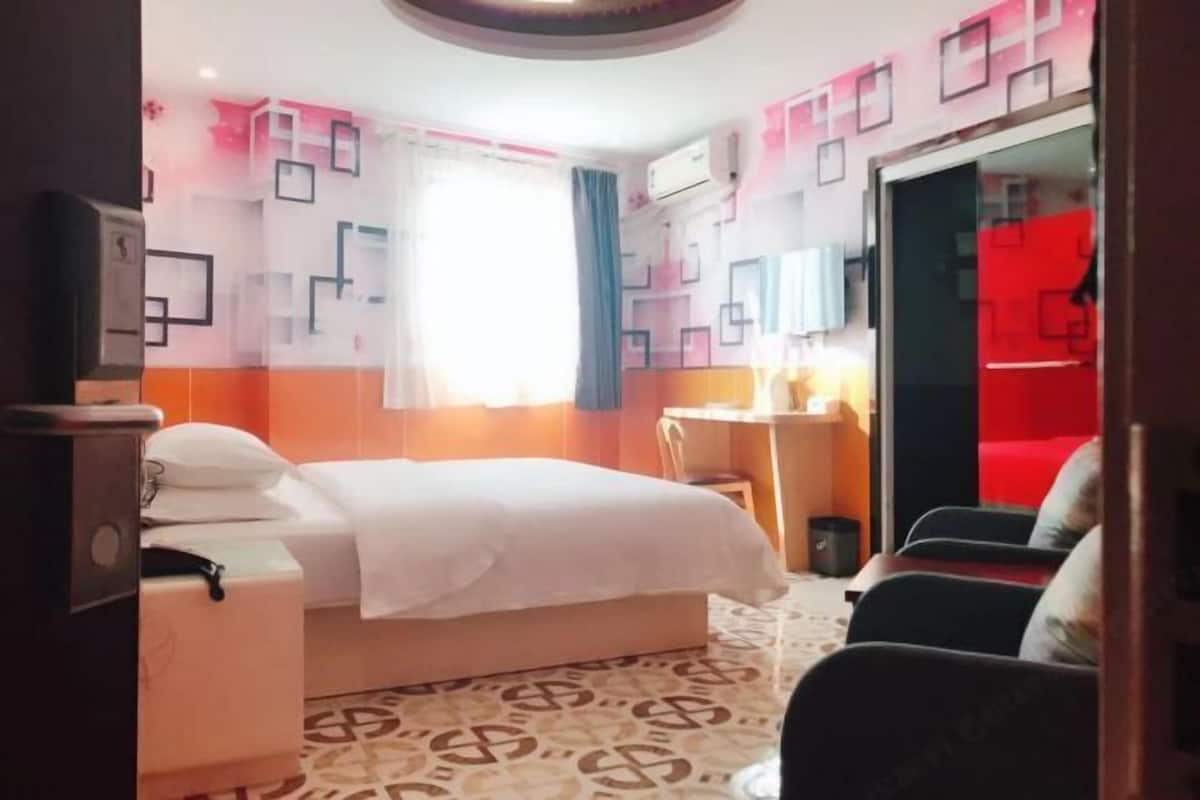 Ein Hotelzimmer mit Bett, Schreibtisch, Stuhl und einer roten Wand.