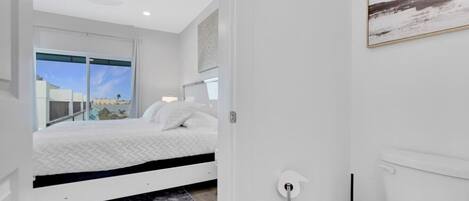 Ein modernes Schlafzimmer mit Bett, Fenster und Blick ins Freie.