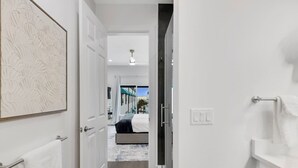 A modern hotel hallway with a bed, a bathroom, and a view of the outside.