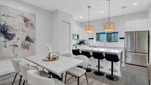 A modern kitchen with a central island, stainless steel appliances, and pendant lighting.