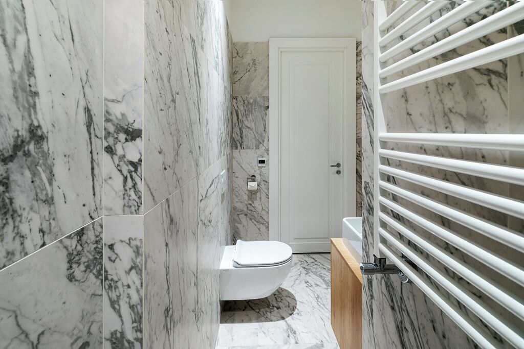Un baño con paredes de mármol y un inodoro blanco.