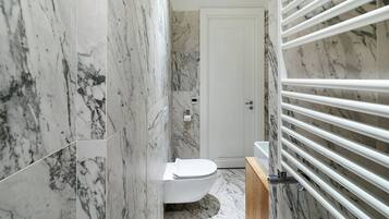 Un baño con paredes de mármol y un inodoro blanco.
