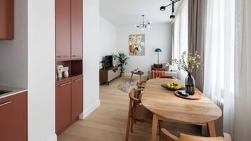 Una cocina moderna con armarios de madera, una mesa de comedor con sillas y vistas a una sala de estar con sofá y plantas.