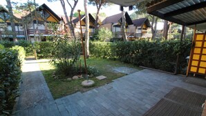 Un patio con un sendero adoquinado, rodeado de vegetación y estructuras de madera.