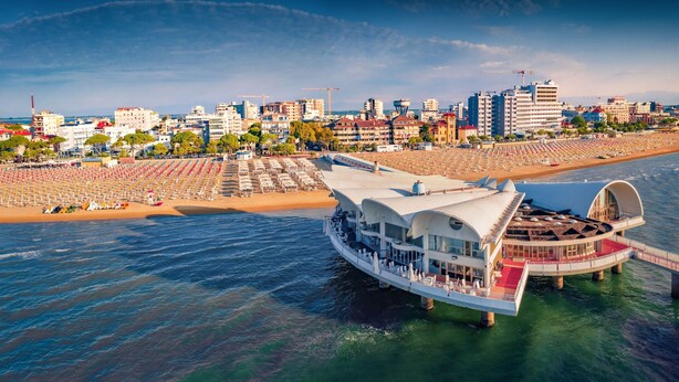 Un hotel frente al agua con una amplia terraza, varios niveles y vista al horizonte de la ciudad.