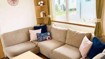 A cozy living room with a sectional sofa, a wooden coffee table, and a decorative clock on the wall.