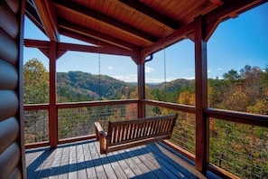 A wooden deck with a bench, a view of a forested mountain range, and a clear sky. - Great location w/VIEWS, wraparound deck, hot tub, arcade, king bd, 0 stairs main (Sevierville)