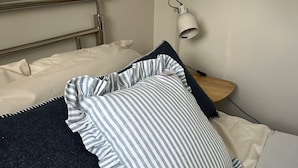 A neatly made bed with striped pillows and a dark throw blanket.