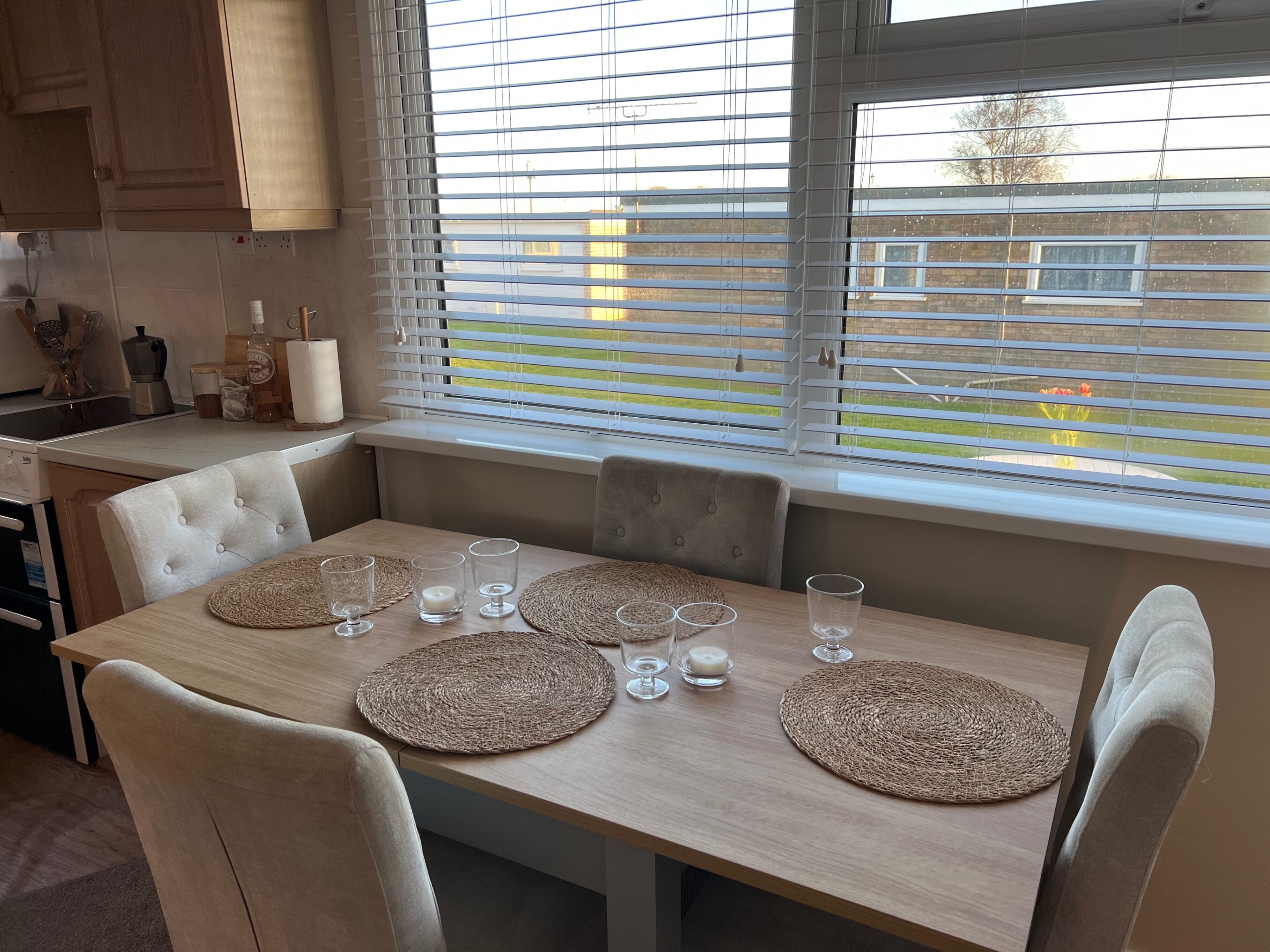 Un coin repas avec une table en bois, dressée pour quatre personnes, entourée de chaises rembourrées.