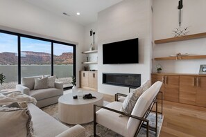 Una sala de estar moderna con un ventanal grande, un televisor de pantalla plana y una chimenea.