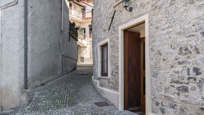 A narrow cobblestone street with stone buildings, a wooden door, and a window with bars. - La Dimora del Borgo - Two Bedroom House, Sleeps 6 (Lierna)