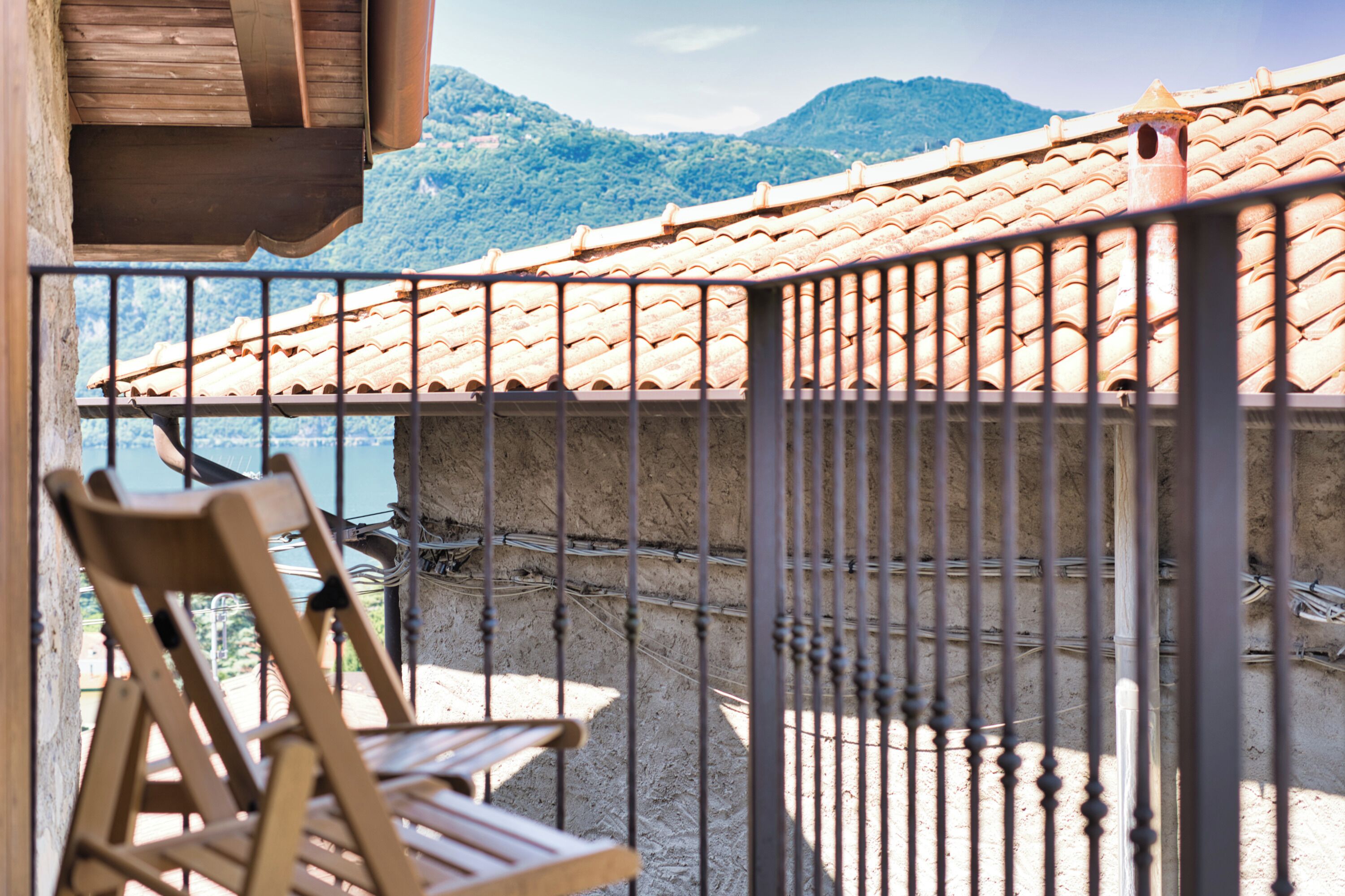 A balcony with a tiled roof, a wooden chair, and a view of mountains.