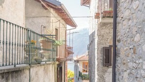 A narrow stone pathway between buildings with balconies and a view of the mountains in the distance. - La Dimora del Borgo - Two Bedroom House, Sleeps 6 (Lierna)