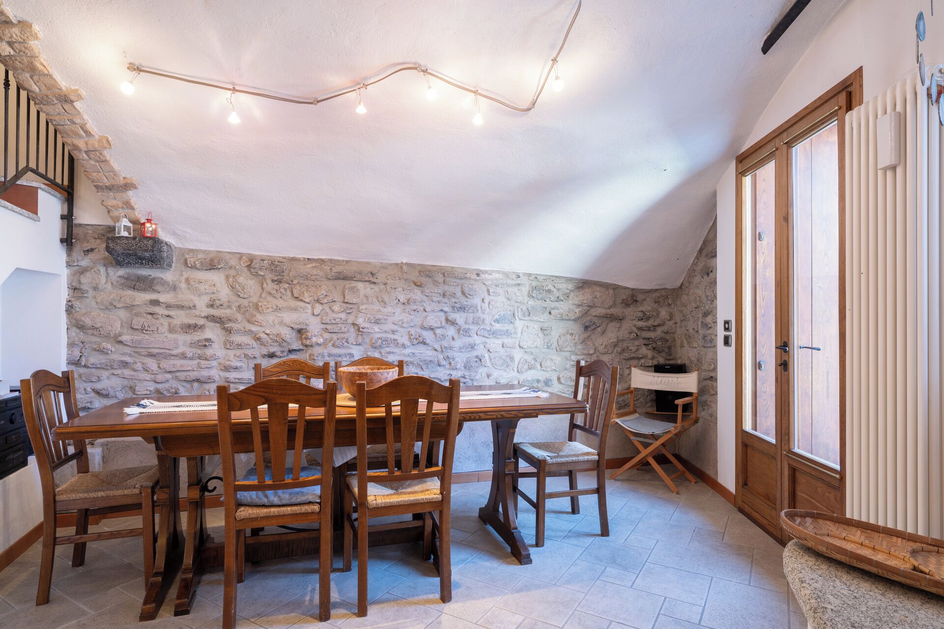 Ein Essbereich mit Steinwand, Holztisch und Stühlen.