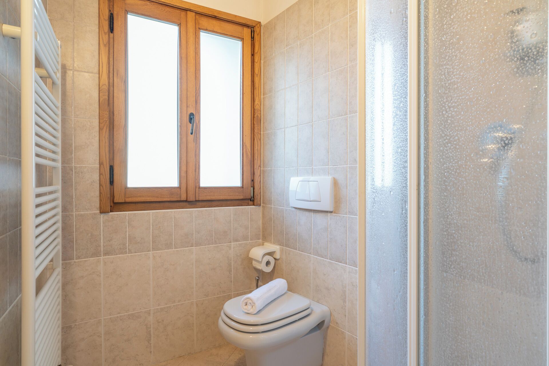Kylpyhuone, jossa on wc, ikkuna ja suihku.