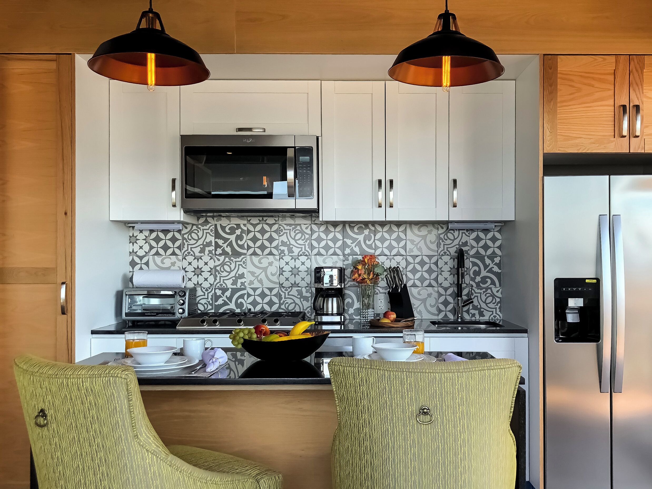 A modern kitchen with white cabinets, a microwave, a coffee maker, and a fruit bowl on the counter.