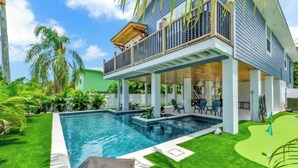 Ein zweistöckiges Haus mit Pool, überdachter Terrasse und üppigem Garten.