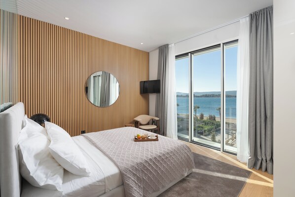 Une chambre d’hôtel avec un grand lit, une télévision, un fauteuil et une vue sur la mer.