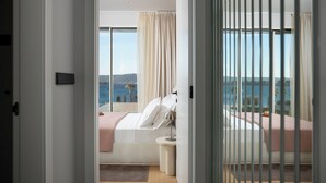 Une chambre à coucher avec un lit, une table de chevet et une vue sur la mer.
