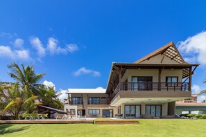 A two-story building with a balcony, a pool, and a lawn. - Mansão Carneiros By Carpediem (Tamandaré)
