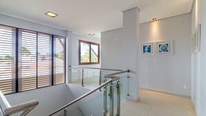 A modern interior with a glass staircase, a view through the window, and artwork on the wall. - Mansão Carneiros By Carpediem (Tamandaré)