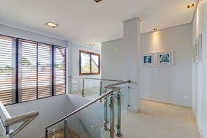 A modern interior with a glass staircase, a view through the window, and artwork on the wall. - Mansão Carneiros By Carpediem (Tamandaré)