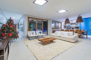A modern living room with a white sofa, a coffee table, and a Christmas tree. - Mansão Carneiros By Carpediem (Tamandaré)