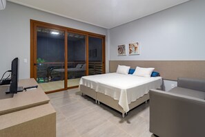A bedroom with a bed, a desk, a chair, and a sliding glass door leading to a balcony. - Mansão Carneiros By Carpediem (Tamandaré)