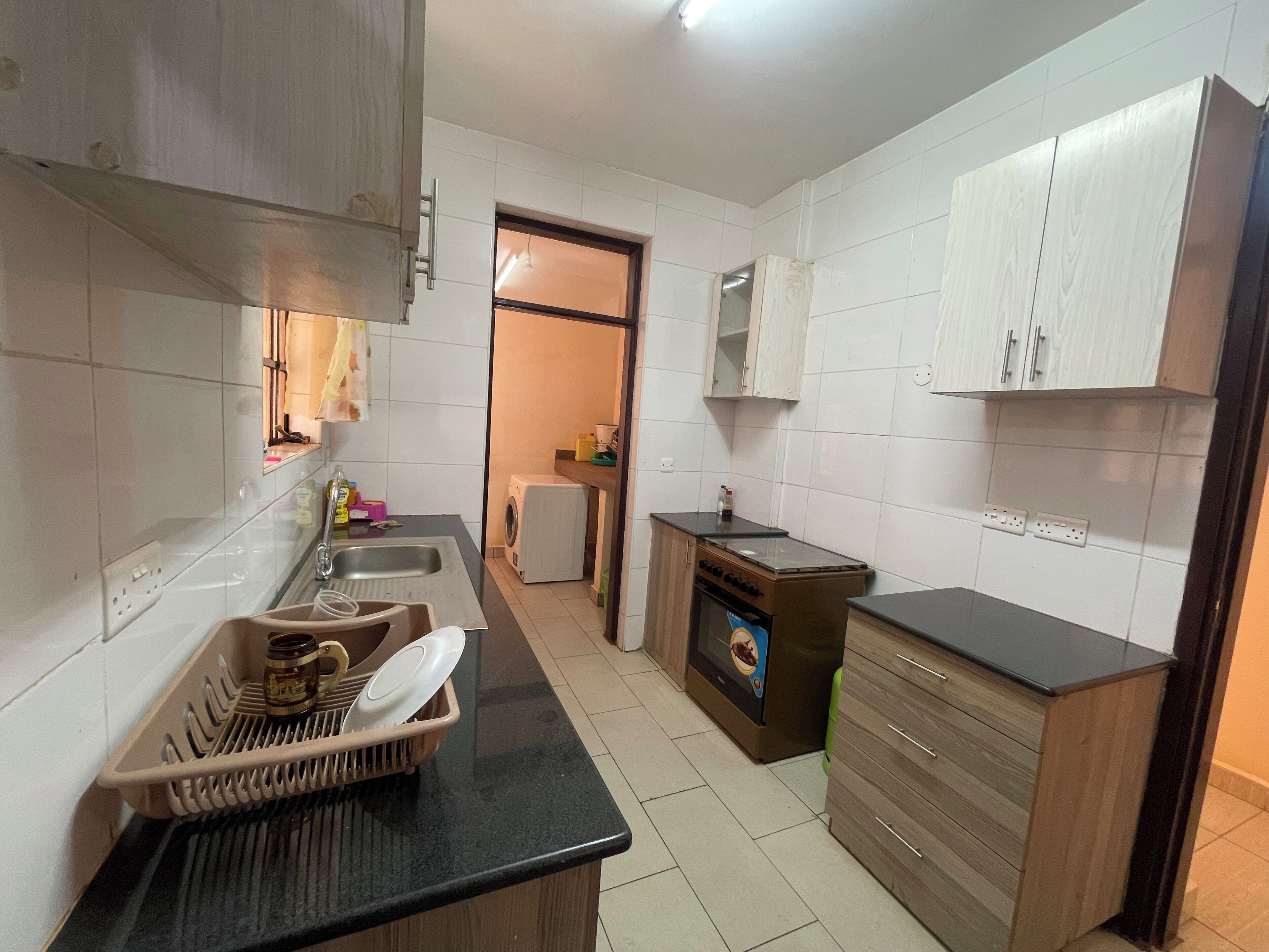 Una cocina compacta con lavamanos, lavadora, estufa y armarios de madera.