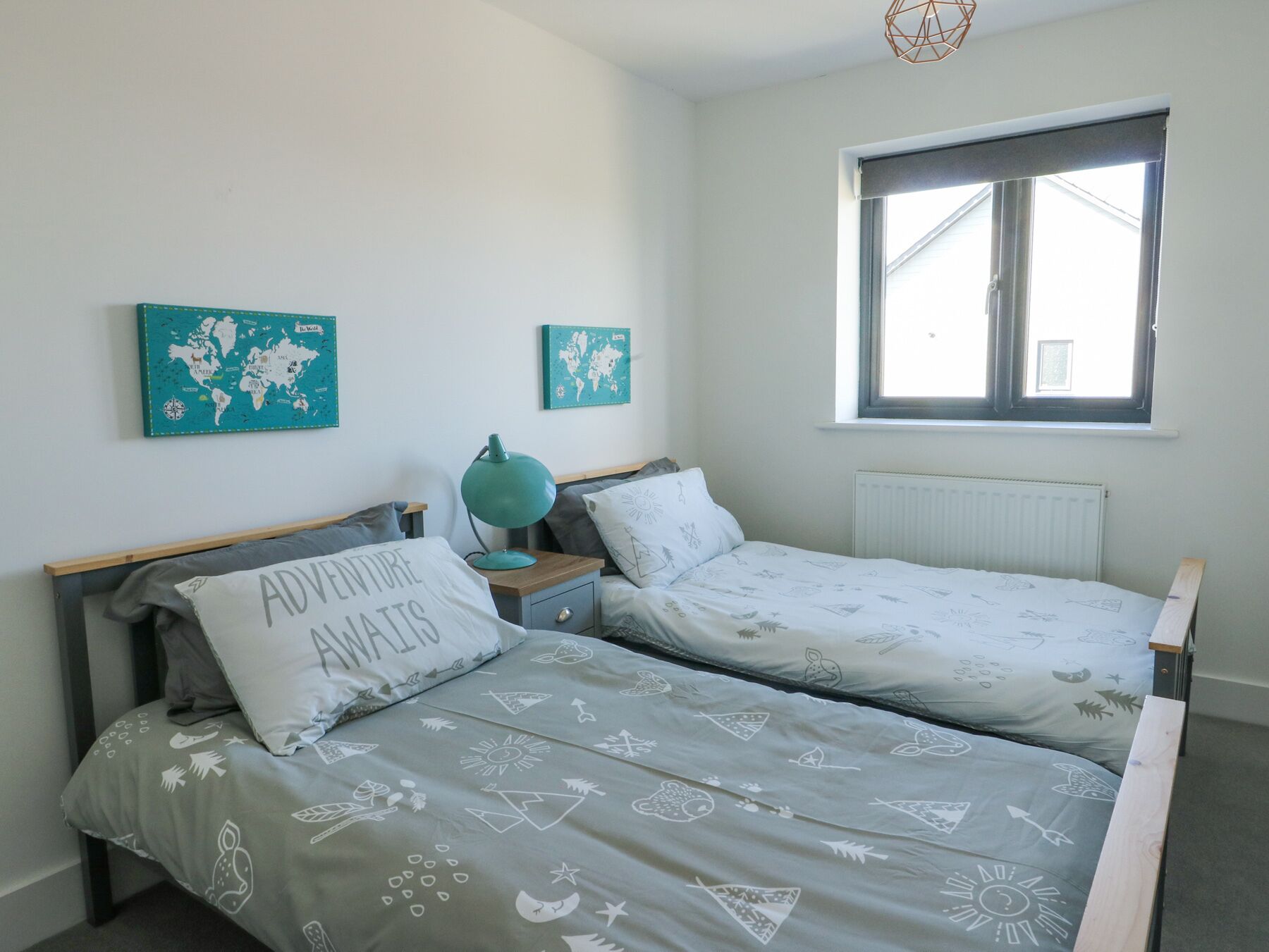 A bedroom with two single beds, a world map on the wall, a window, and a radiator.