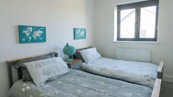 A bedroom with two single beds, a world map on the wall, a window, and a radiator.