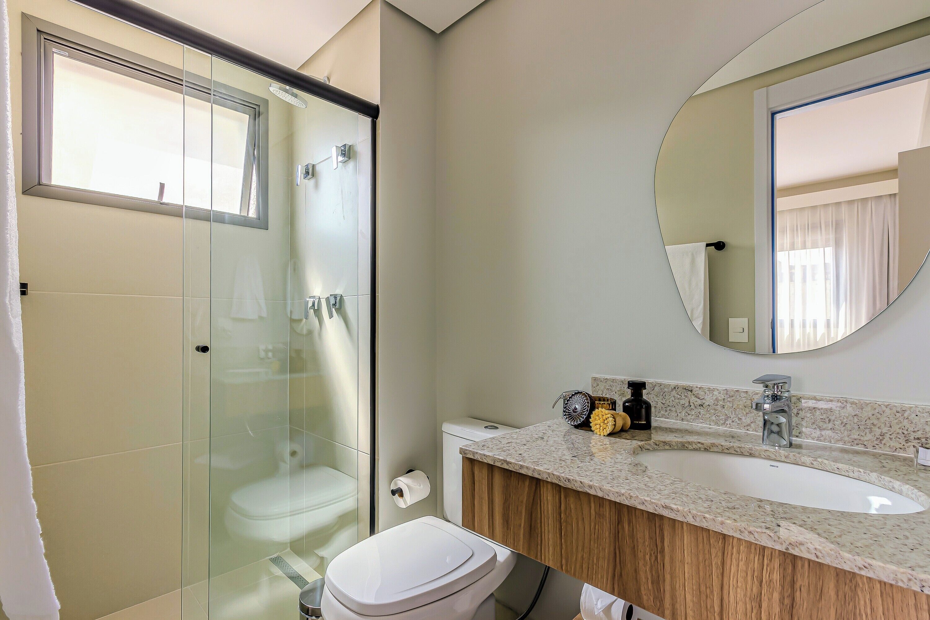 Ein modernes Badezimmer mit einer Duschkabine, einer weißen Toilette und einer Waschtischplatte aus Granit mit Waschbecken und Spiegel.