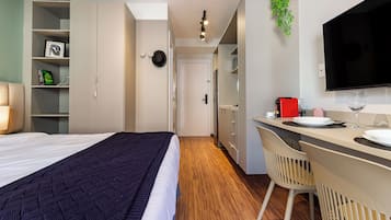 Una habitación de hotel moderna con una cama, un escritorio con silla, un televisor y una estantería.
