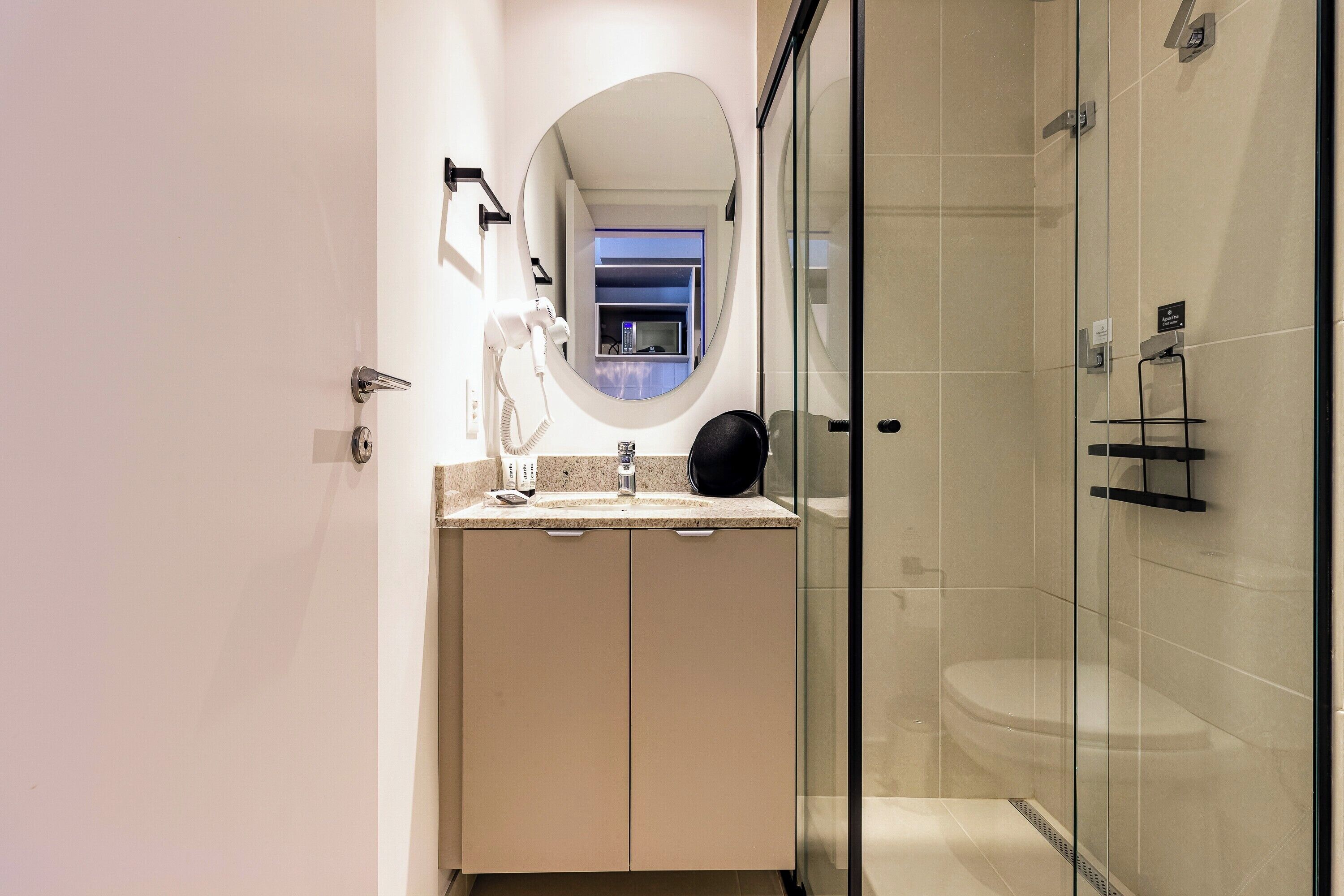 A modern bathroom with a glass shower enclosure, a vanity with a sink, and a mirror.