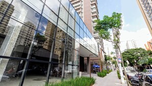 A modern building with reflective glass facade, a visible entrance, and a clear sky. - Charlie Grand Vitrali Moema (São Paulo)