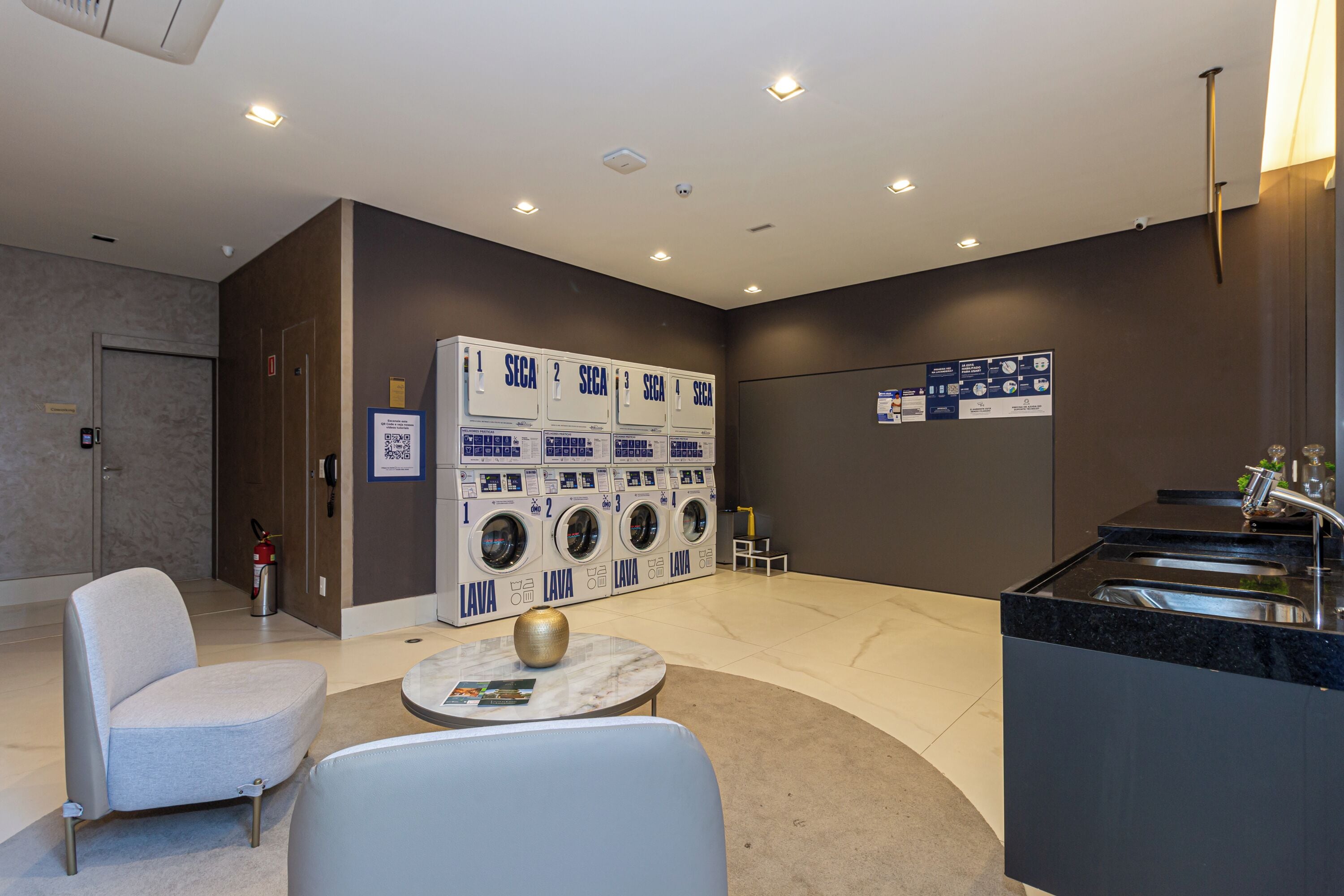 Een hotel lobby met een zithoek, een self-service wasserij en een receptiebalie.