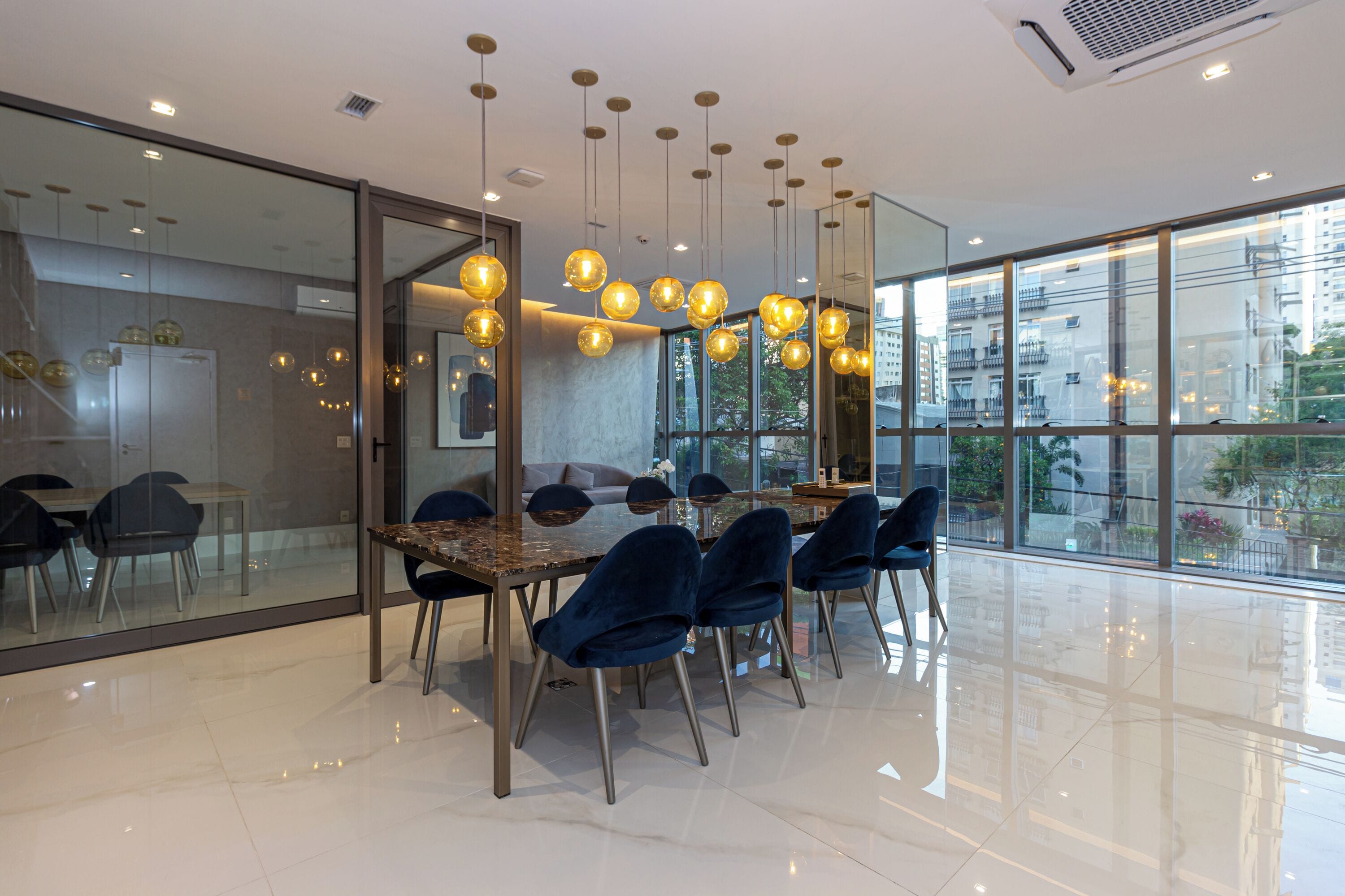 A modern conference room with a glass wall, a polished floor, and hanging spherical light fixtures.