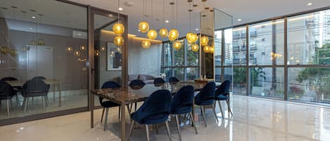 A modern conference room with a glass wall, a polished floor, and hanging spherical light fixtures.