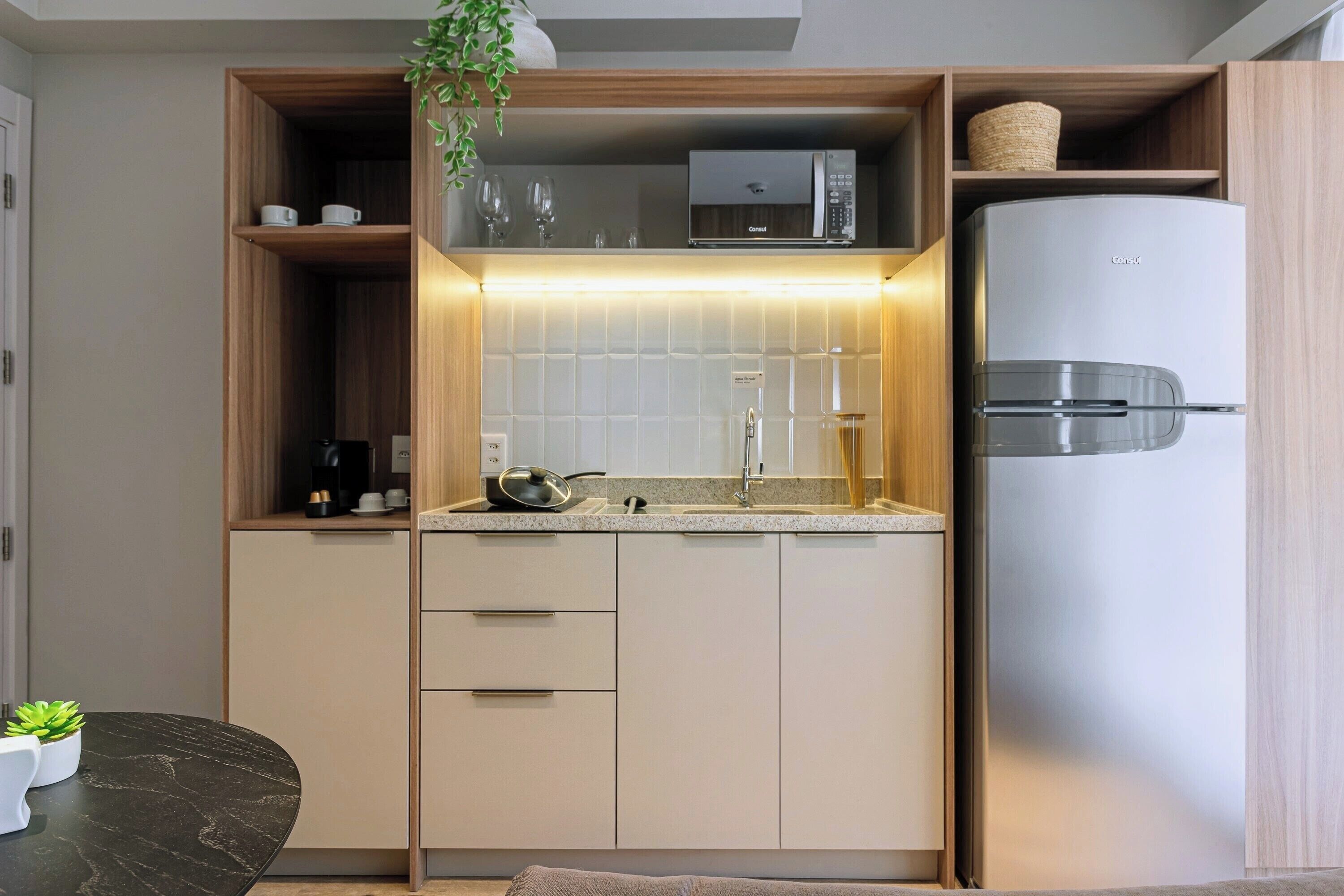 A modern kitchen with built-in appliances, a countertop, and a dining area with a table and chairs.