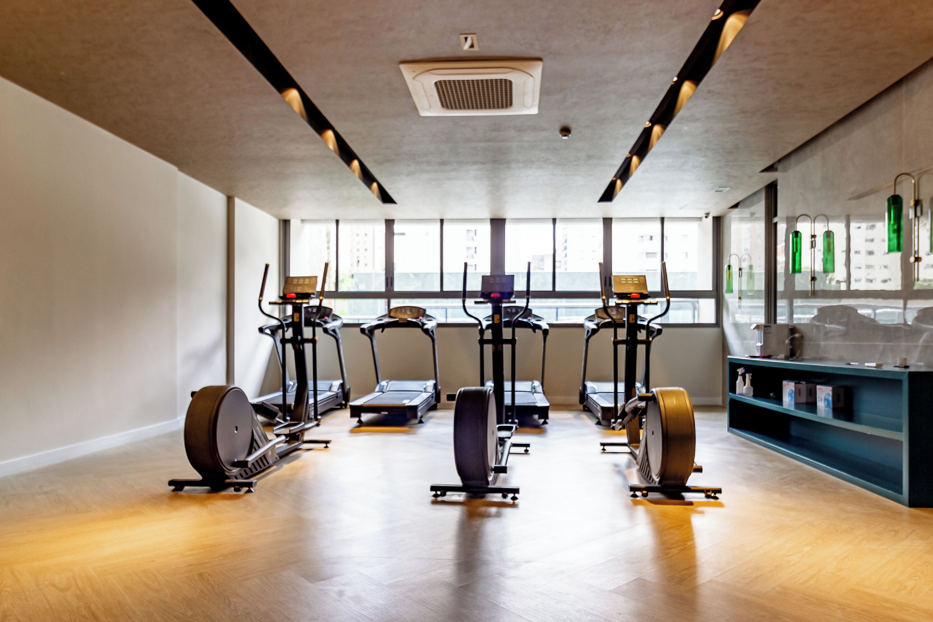 Un gimnasio con equipo de ejercicio, amplias ventanas y suelo de madera.